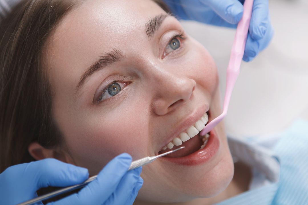 Blue-tinted dental mirror and tools on a white surface, close-up