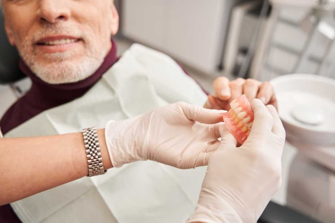 Dentist fitting a clear dental aligner onto a patient’s teeth in a clinic
