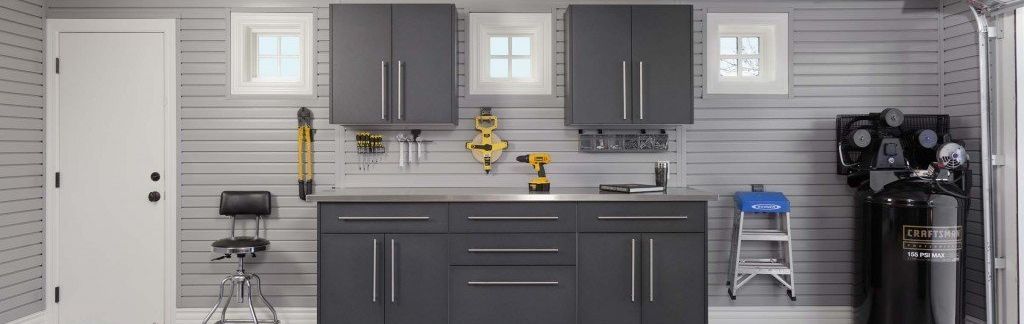 A garage with gray cabinets and a stainless steel counter top.