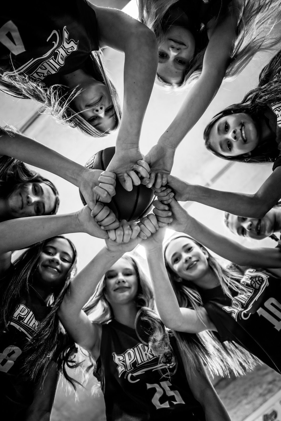 Group of smiling teammates huddle in a circle, hands stacked together in the center.