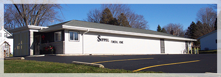 A large building with a curved roof is sitting on the side of the road.