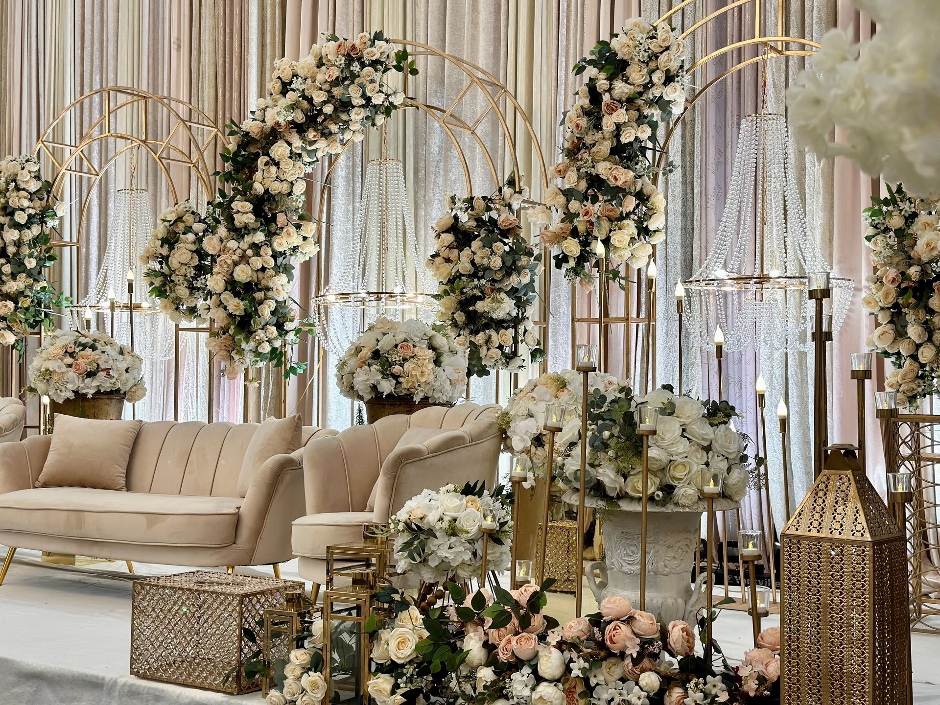Couches and chairs on a wedding reception stage with flowers hanging above