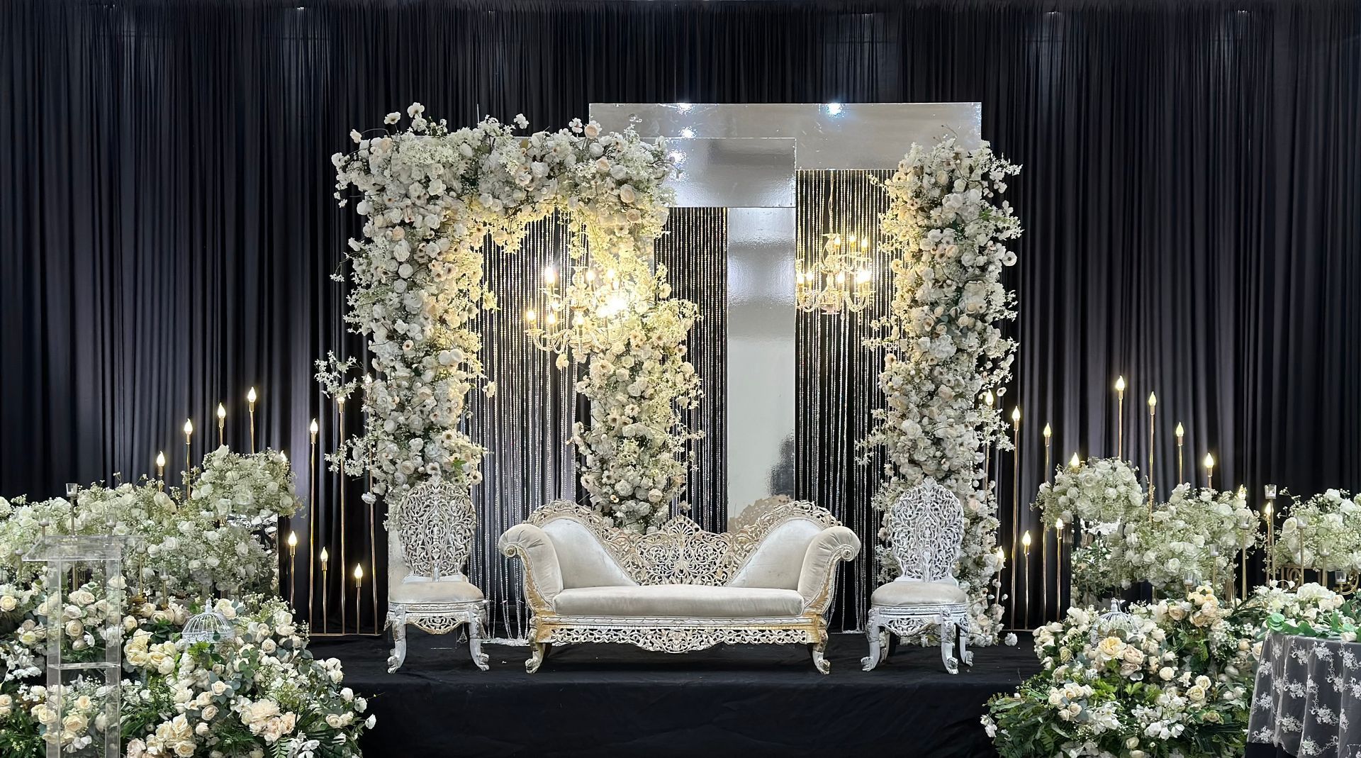 A dark curtain behind a bright floral display with a sofa installed by The Wedding Boutique for an Indian wedding in Toronto