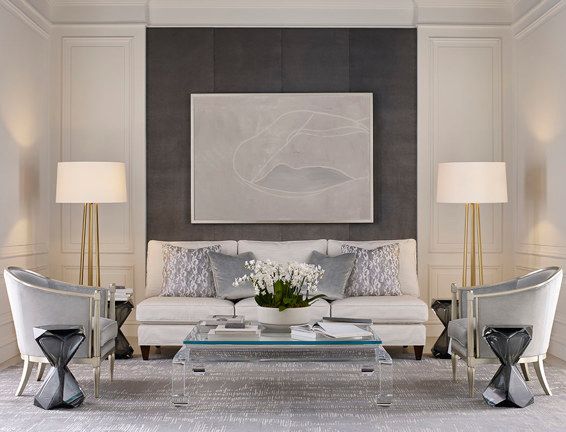 A living room with a couch , chairs , lamps and a coffee table
