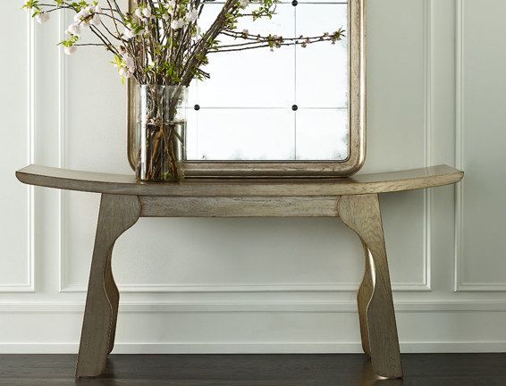A table with a vase of flowers and a mirror on it