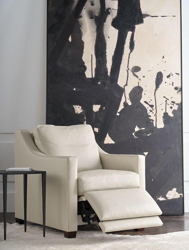 A white recliner in front of a large black and white painting
