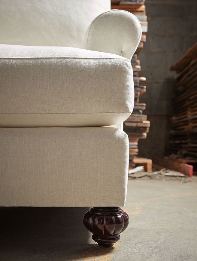 A white chair with wooden legs is sitting on a concrete floor.