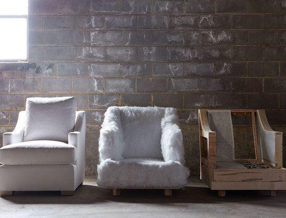 Three chairs are lined up in front of a brick wall.