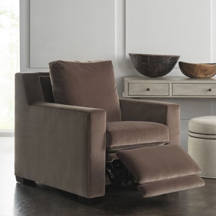 A brown recliner is sitting in a living room next to two bowls.