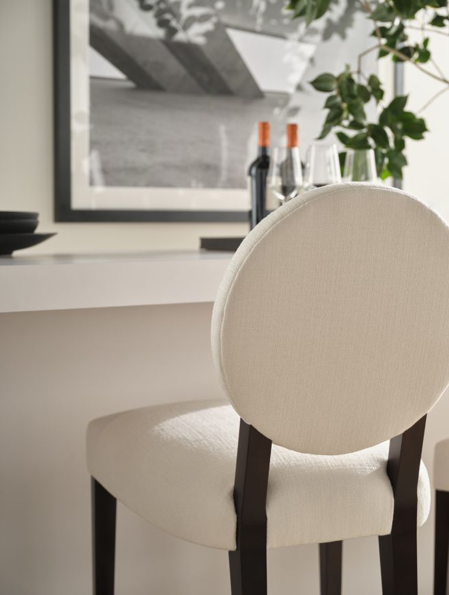 A chair is sitting in front of a table with bottles of wine and glasses on it