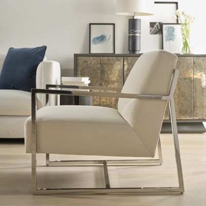 A white chair is sitting in a living room next to a couch.