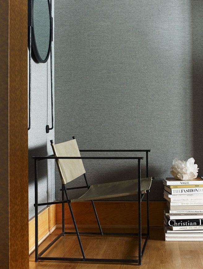 A chair is sitting next to a stack of books in a room.