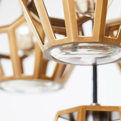 A close up of a brass chandelier with a clear glass shade
