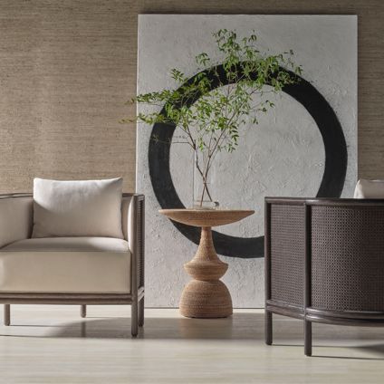 A living room with two chairs , a table and a painting on the wall.