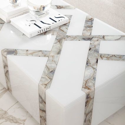 A white coffee table with a book on top of it.