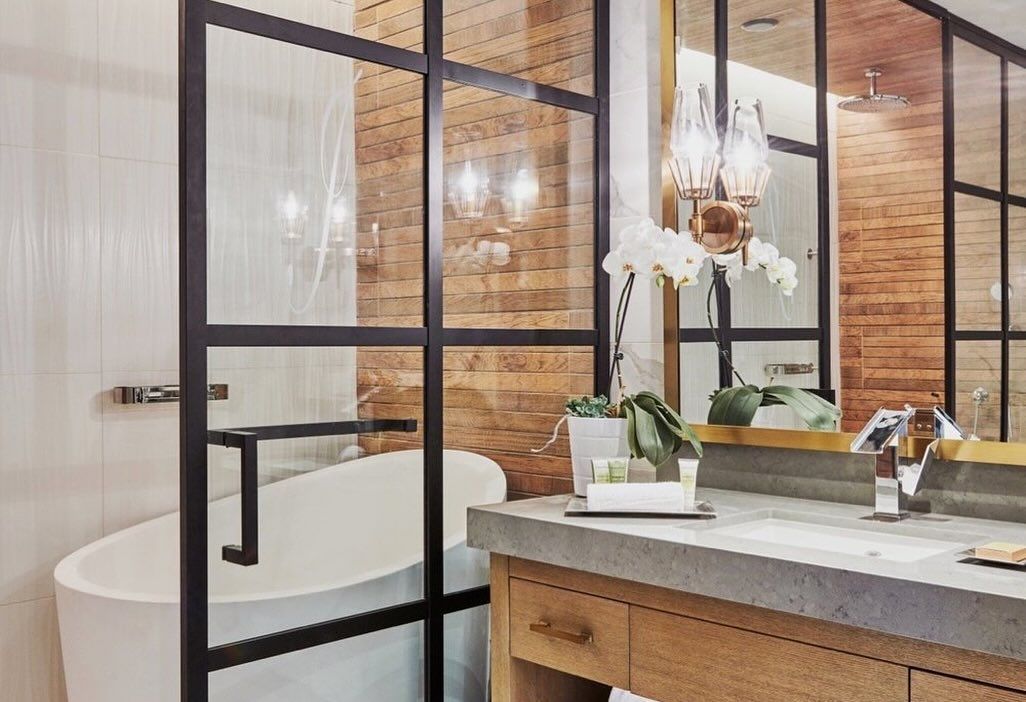 A bathroom with a tub , sink and mirror.