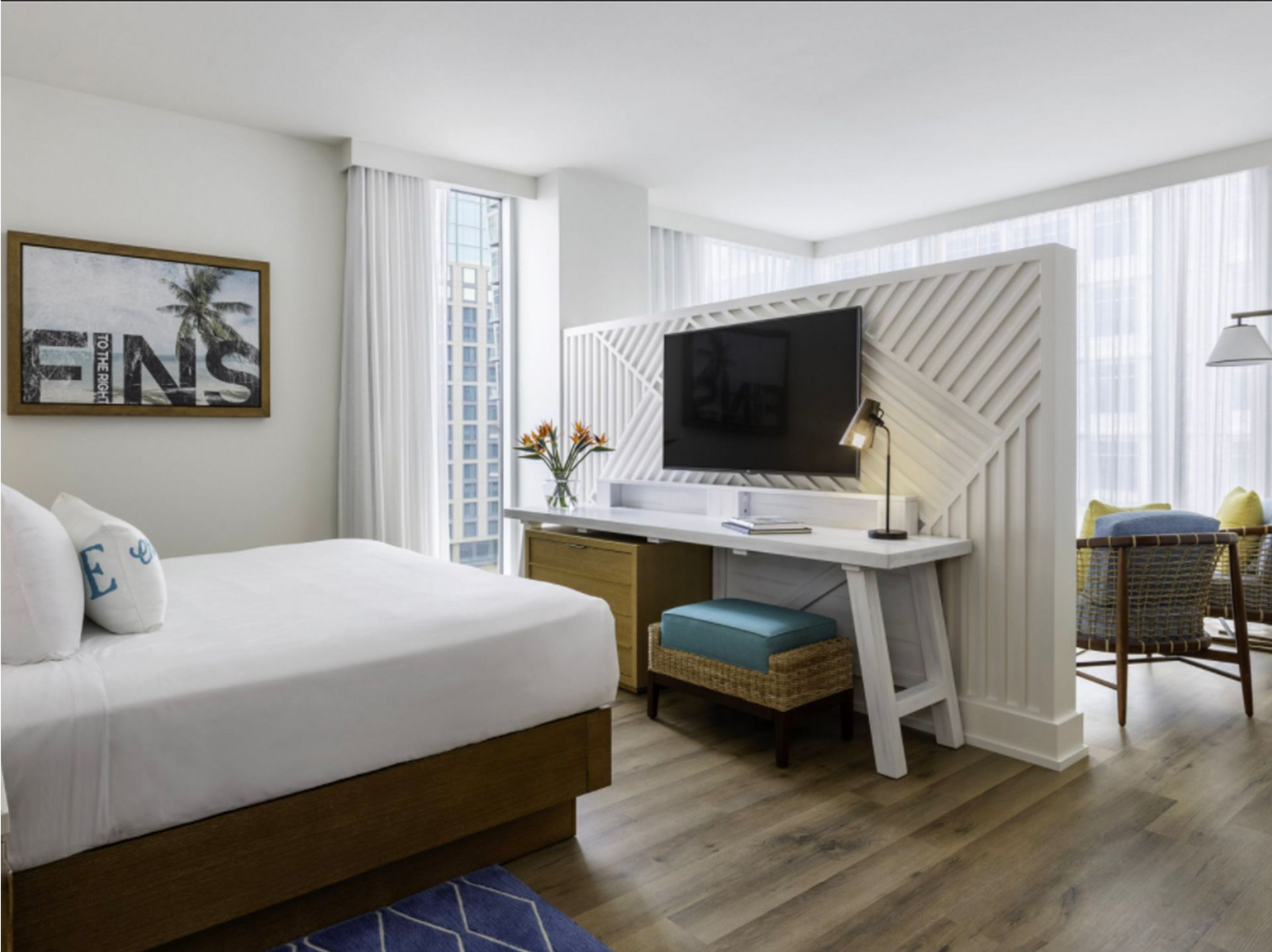 A hotel room with a king size bed , desk , chair and television.