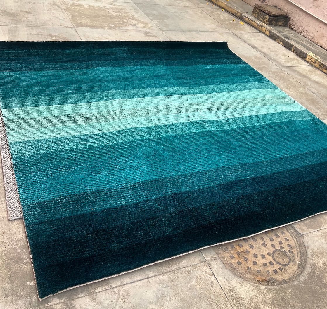 A blue rug with a striped pattern is sitting on the ground.