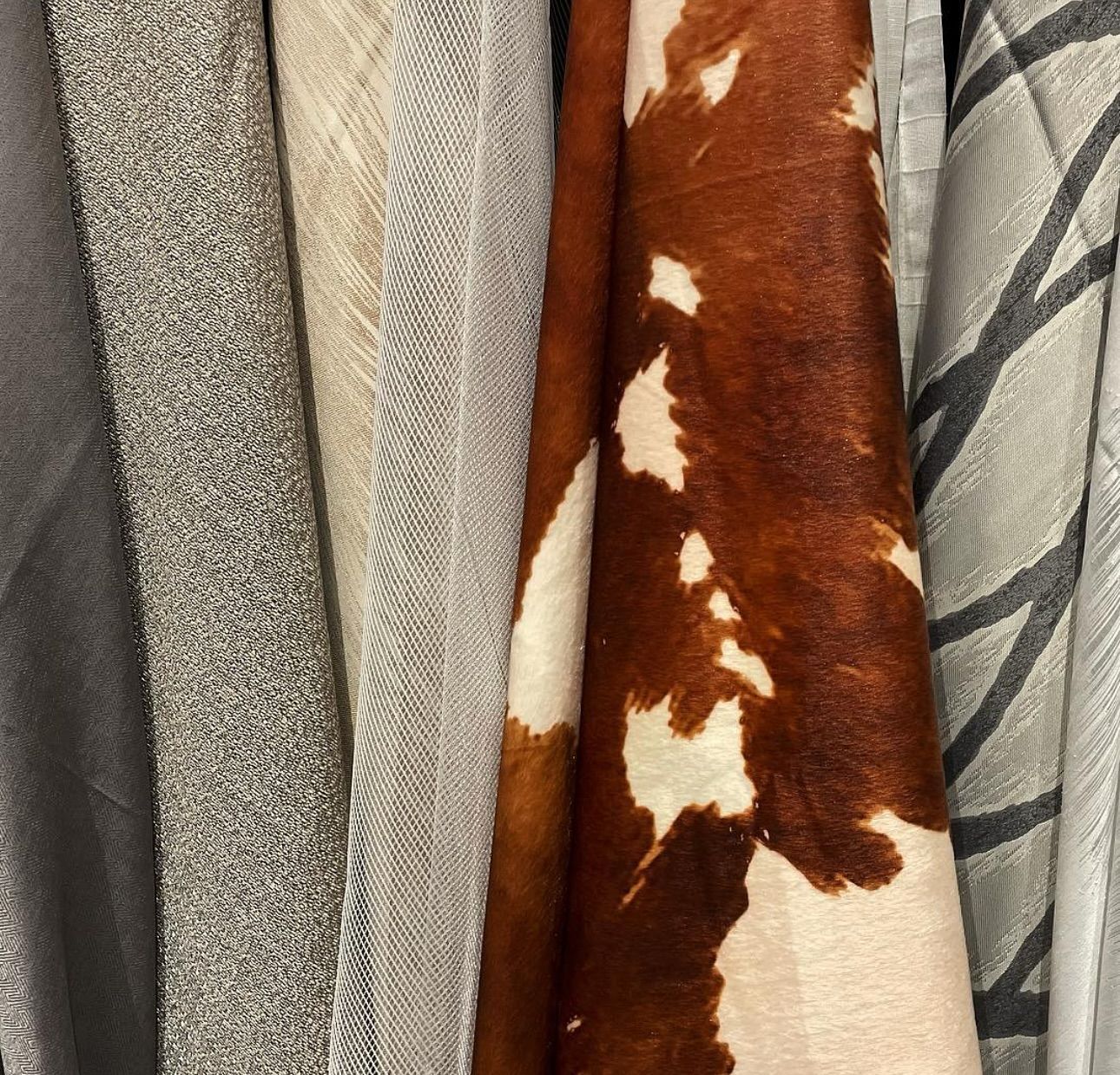 A close up of a brown and white cow print scarf