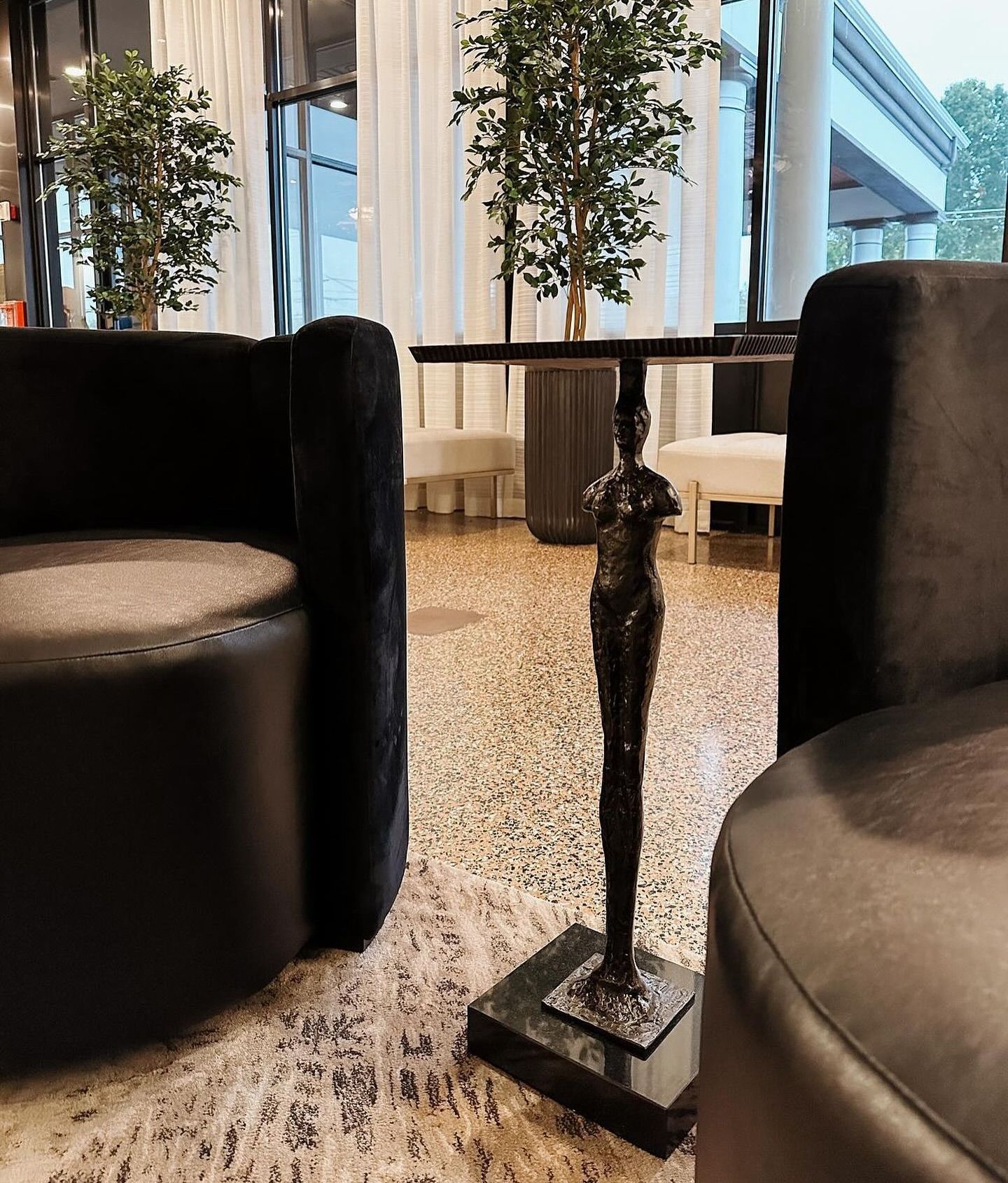 Two black chairs and a table with a statue on it