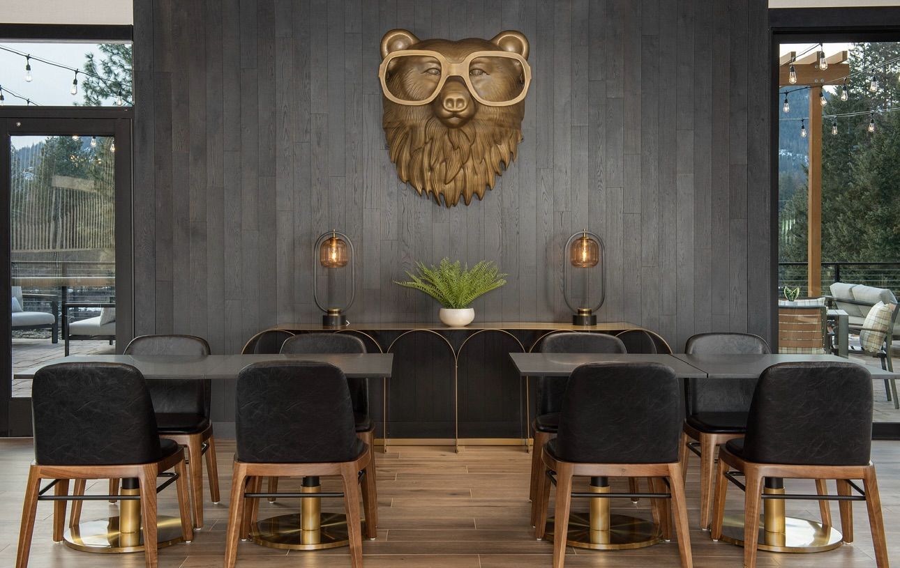 A dining room with tables and chairs and a bear head on the wall.