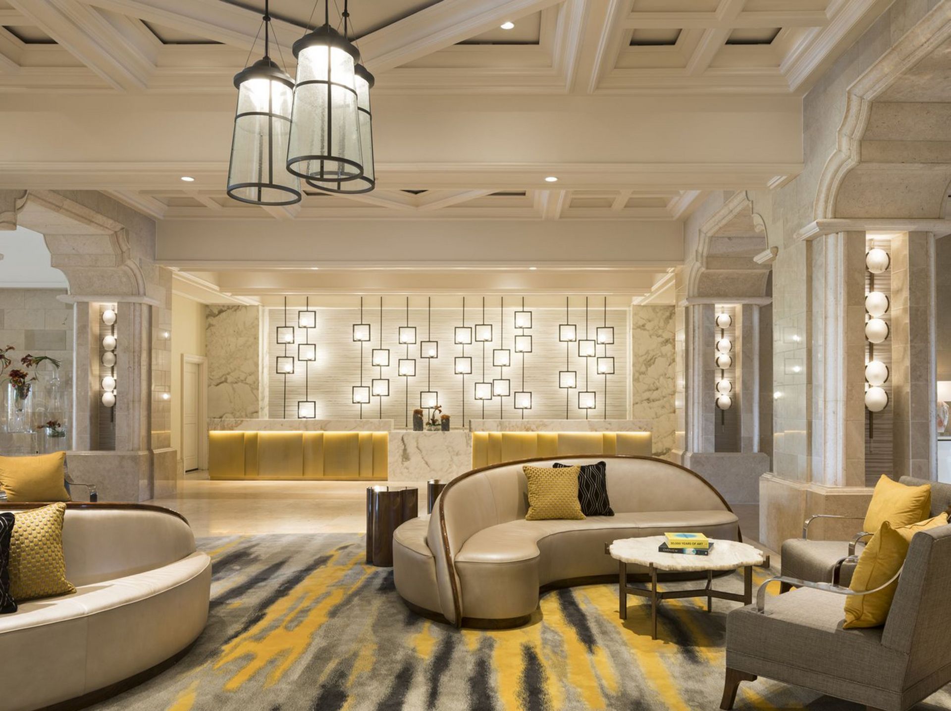 A living room with a couch , chairs , tables and a chandelier.