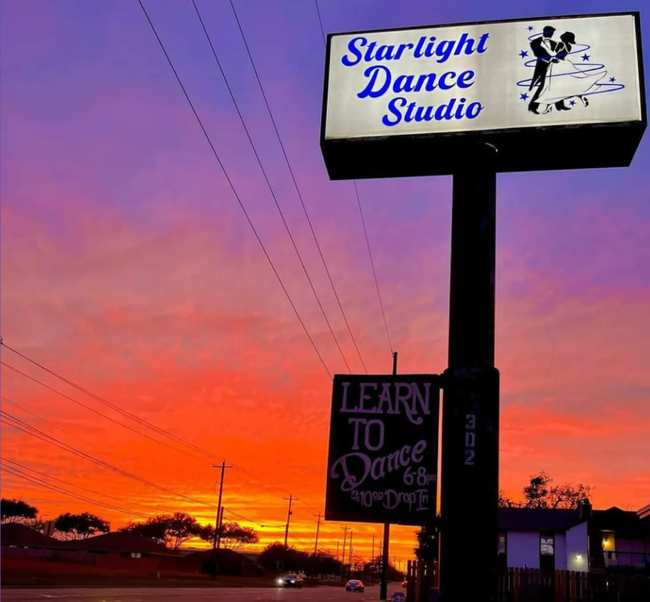 Starlight Dance Studio sign against a vivid orange and purple sunset sky