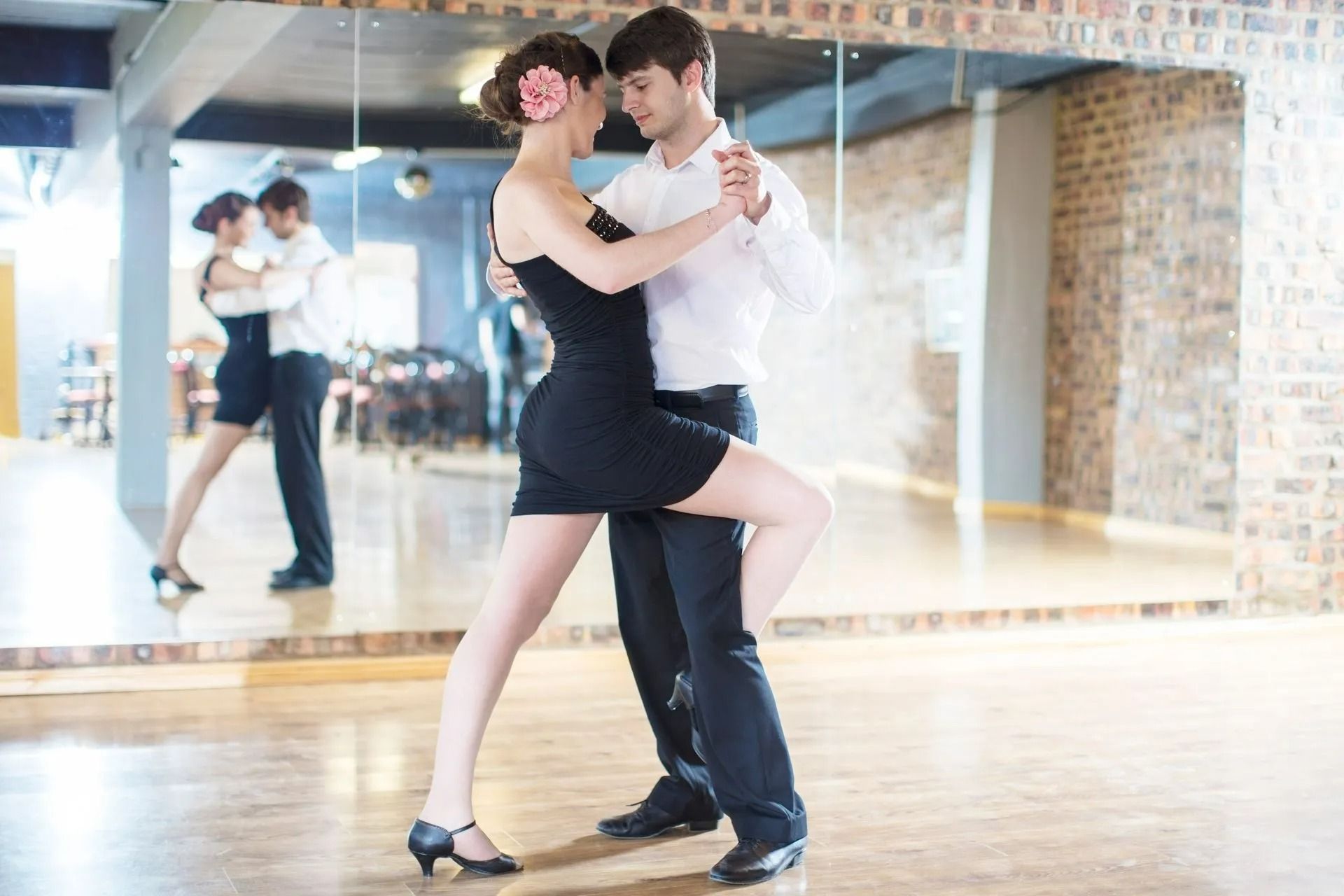 Couple dancing in a studio with mirrored wall and wooden floor