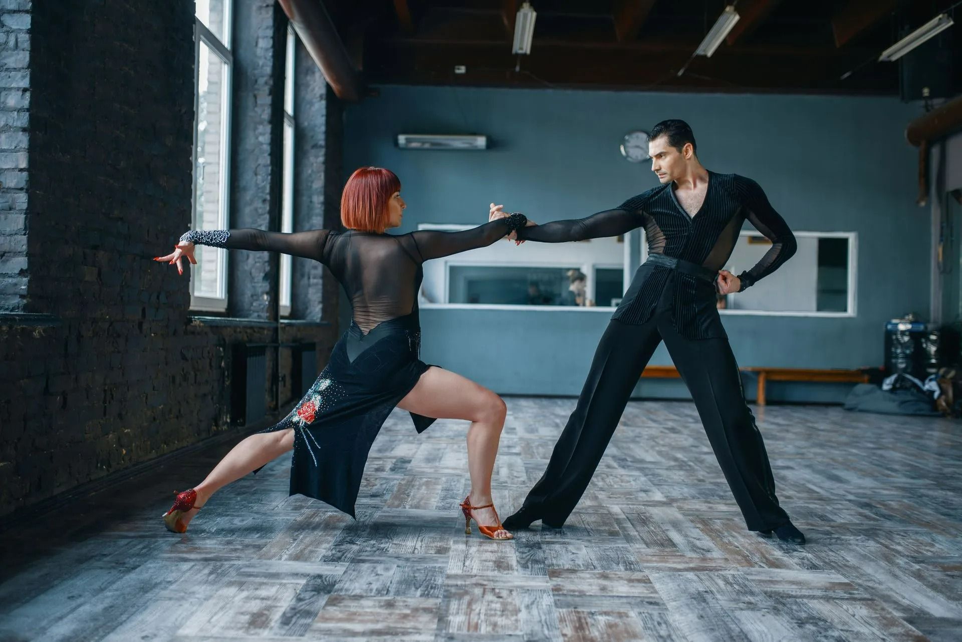 Two dancers in a studio, lunging and reaching toward each other in a dramatic pose.
