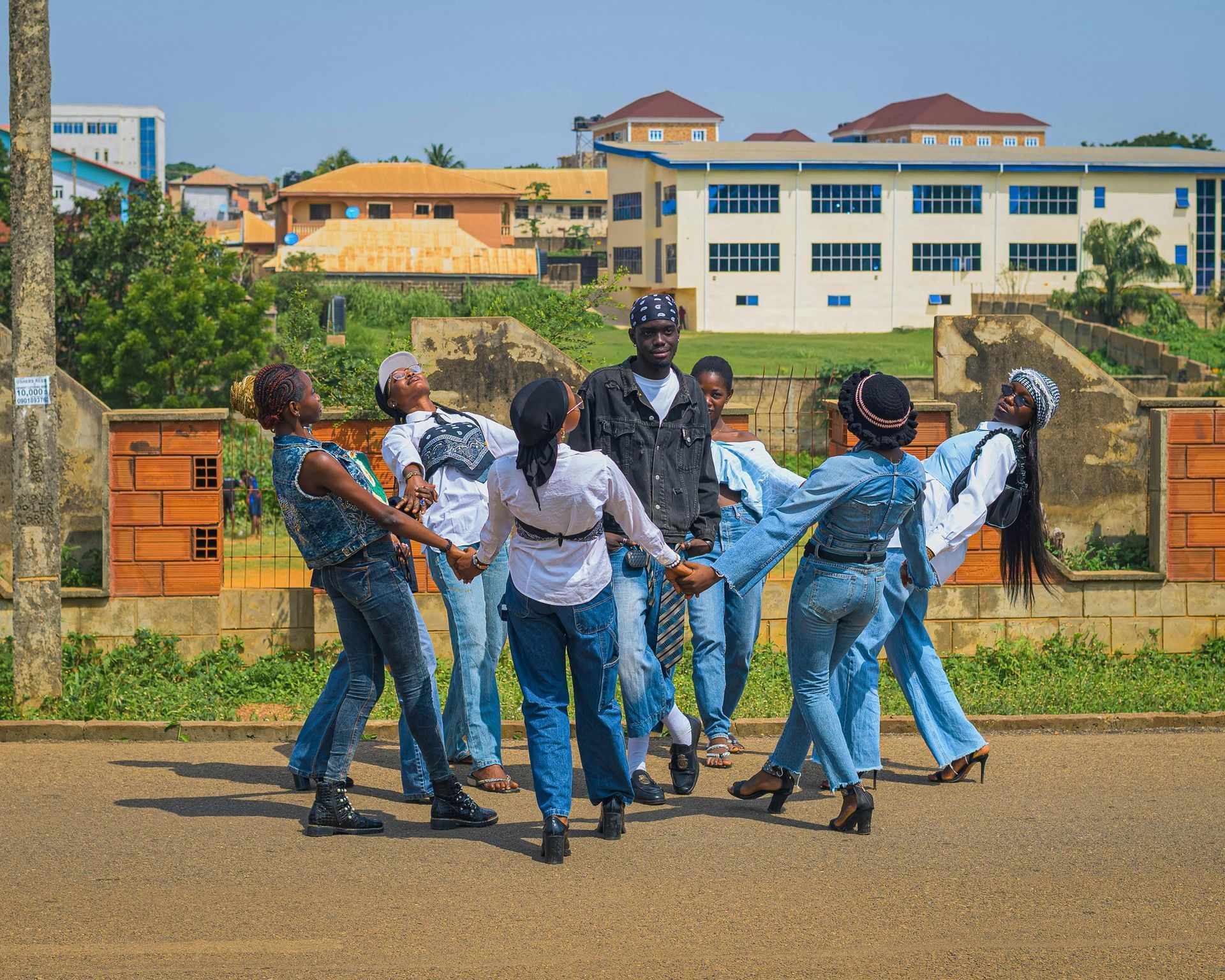 Group of students dancing in a courtyard before a school building under a clear sky