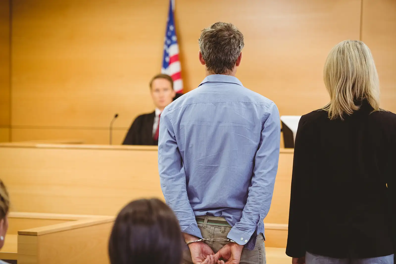 A man wearing handcuffs in court, representing the topic of felonies in criminal defense law.