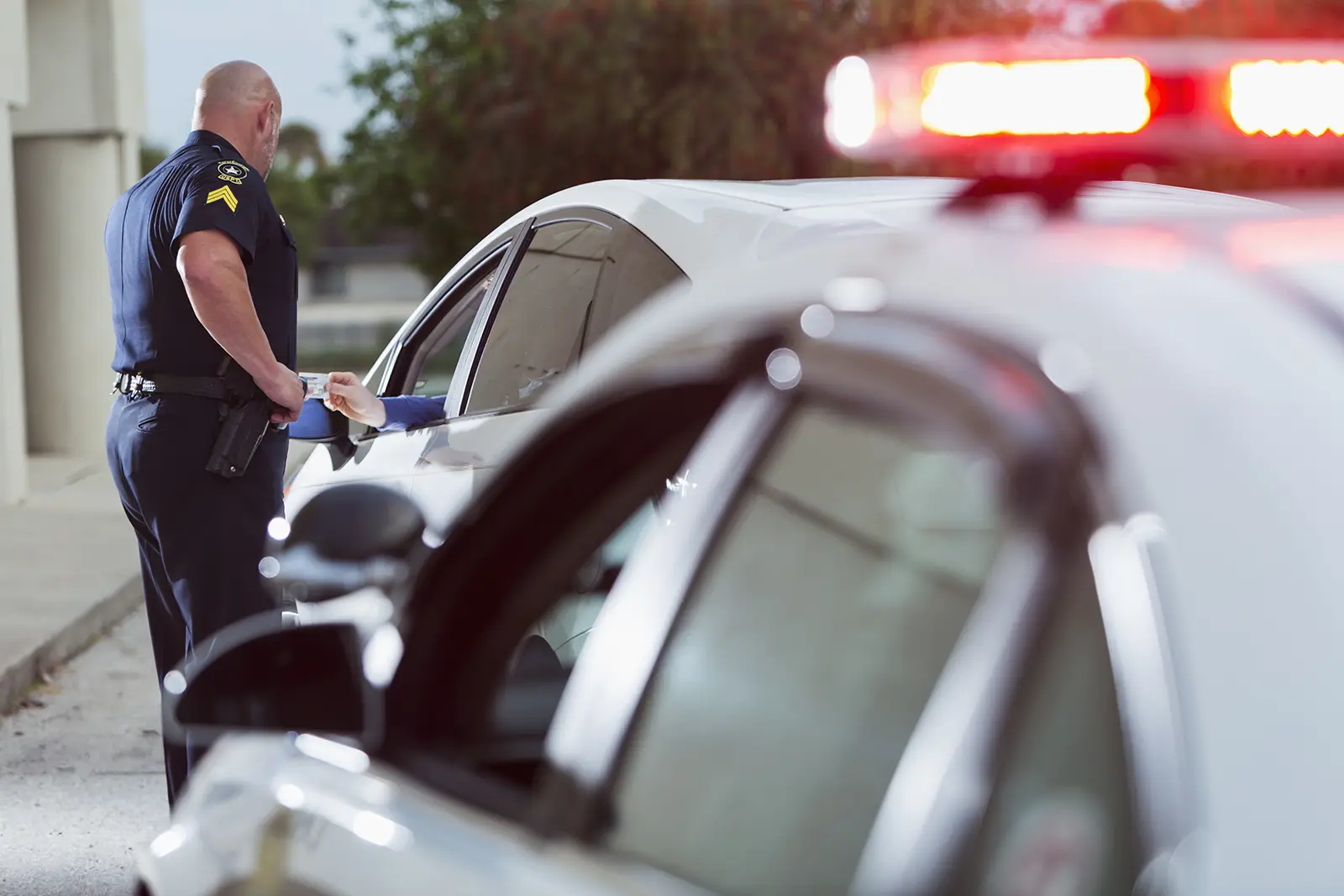 A police officer is standing next to a car, representing the topic of DUI defense law.