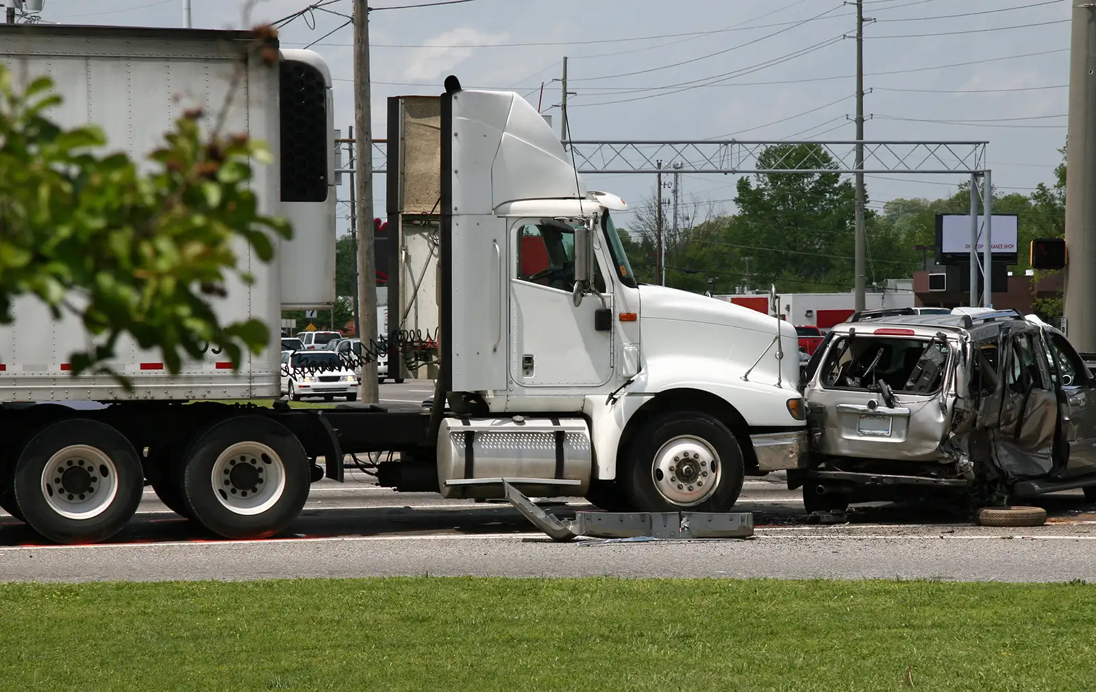 A white semi truck is parked next to a damaged car, representing the topic of truck accidents in personal injury law.