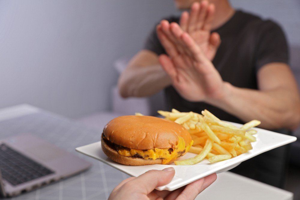 Un uomo si rifiuta di mangiare un hamburger e delle patatine fritte.