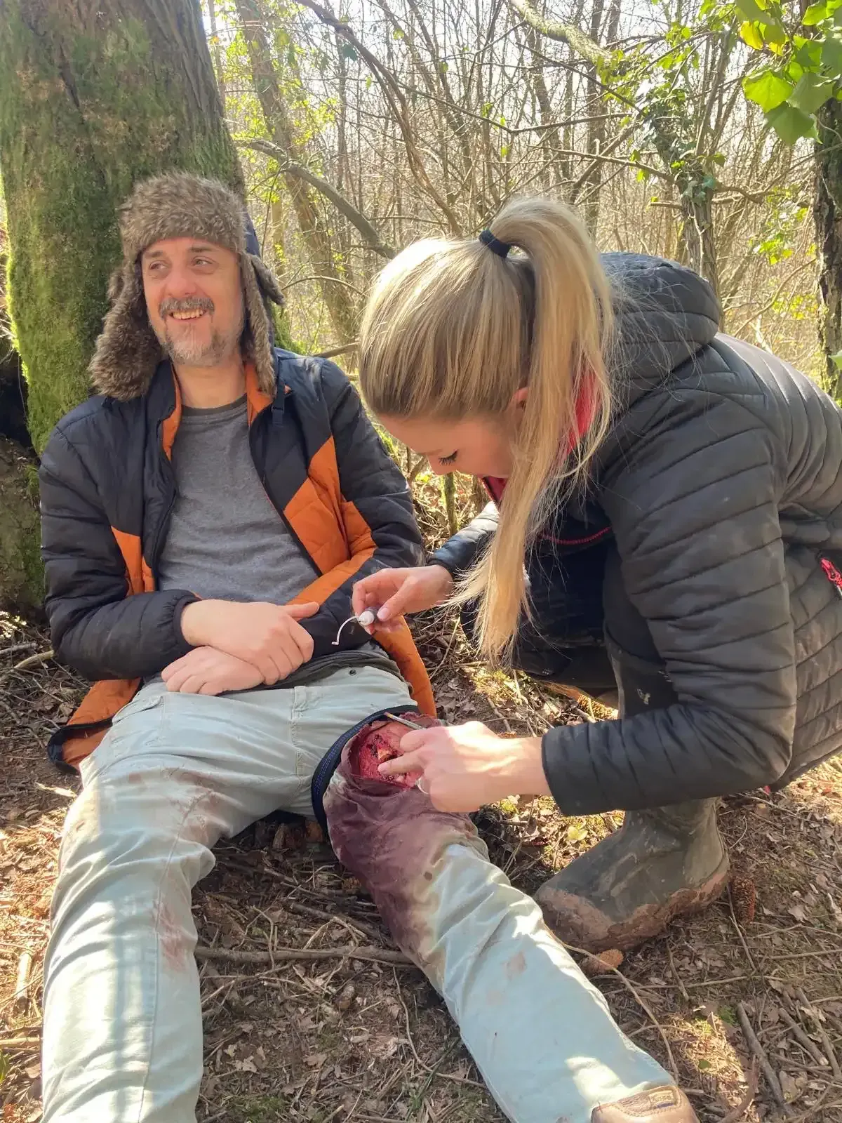 Animal carcass, abdomen open, internal organs visible, person in sweater examines it.