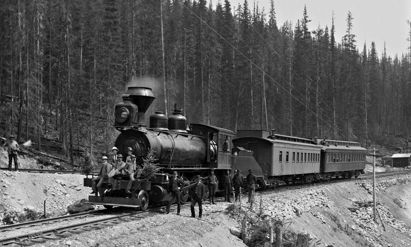 Steam locomotive pulling passenger cars through a snowy forest