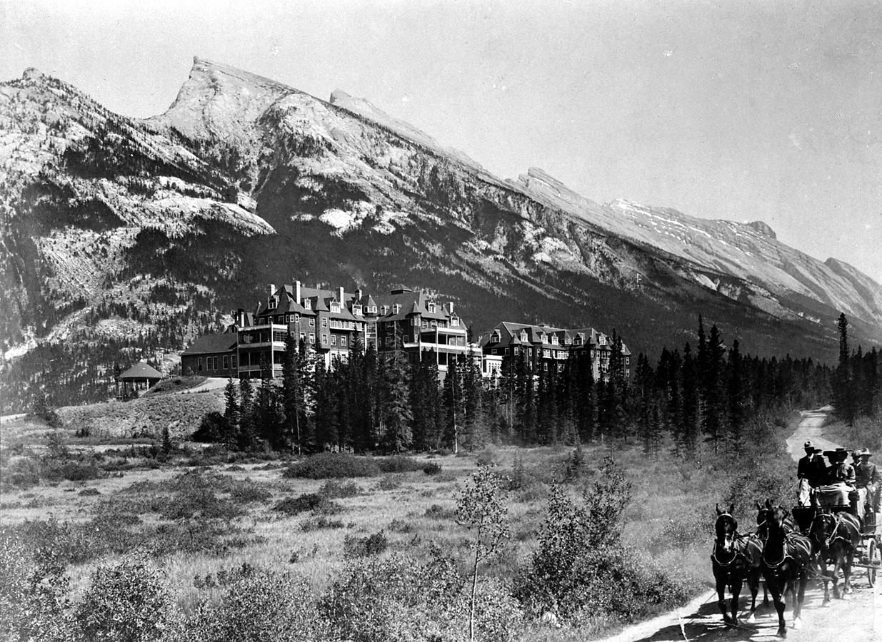 Snowy mountain landscape with a small settlement and horse-drawn wagon in the foreground