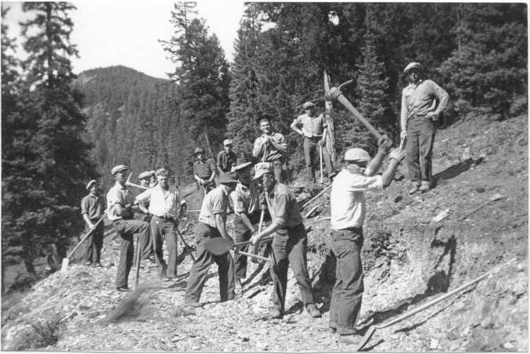 Hikers with walking sticks on a steep mountain trail in a forested area