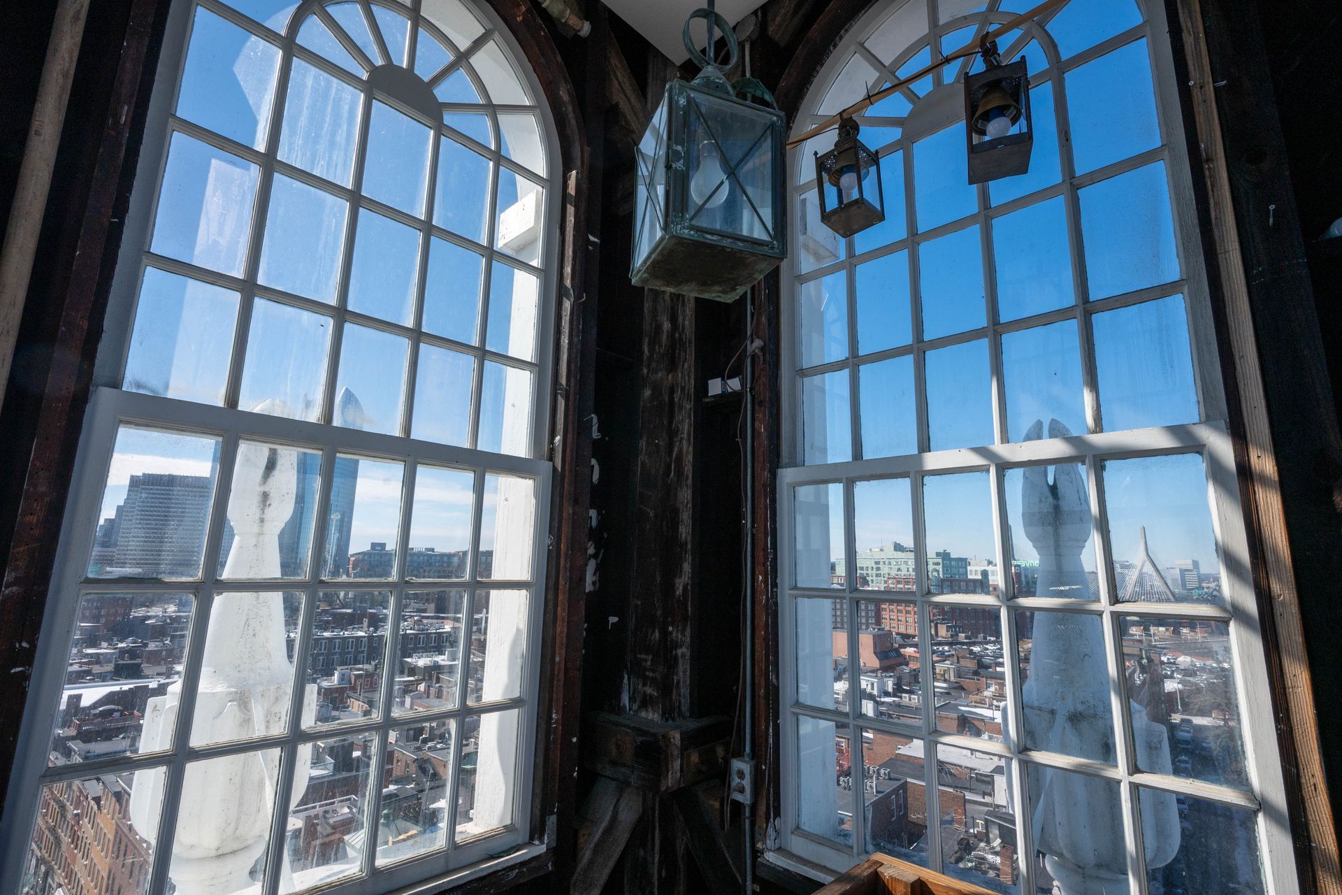 Sunlit view through arched windows overlooking a city skyline and blue sky