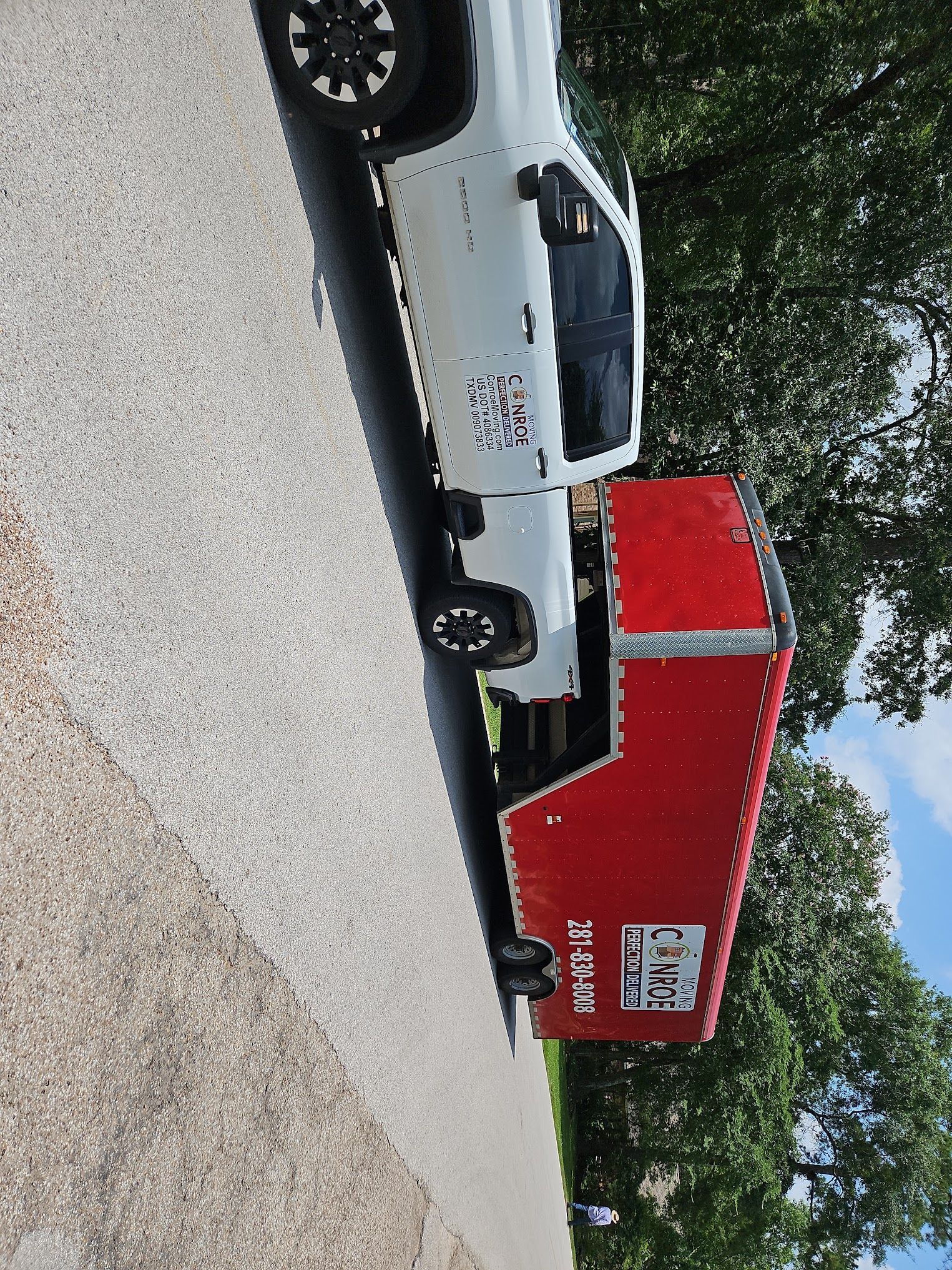 A white truck is parked on the side of the road next to a red trailer.