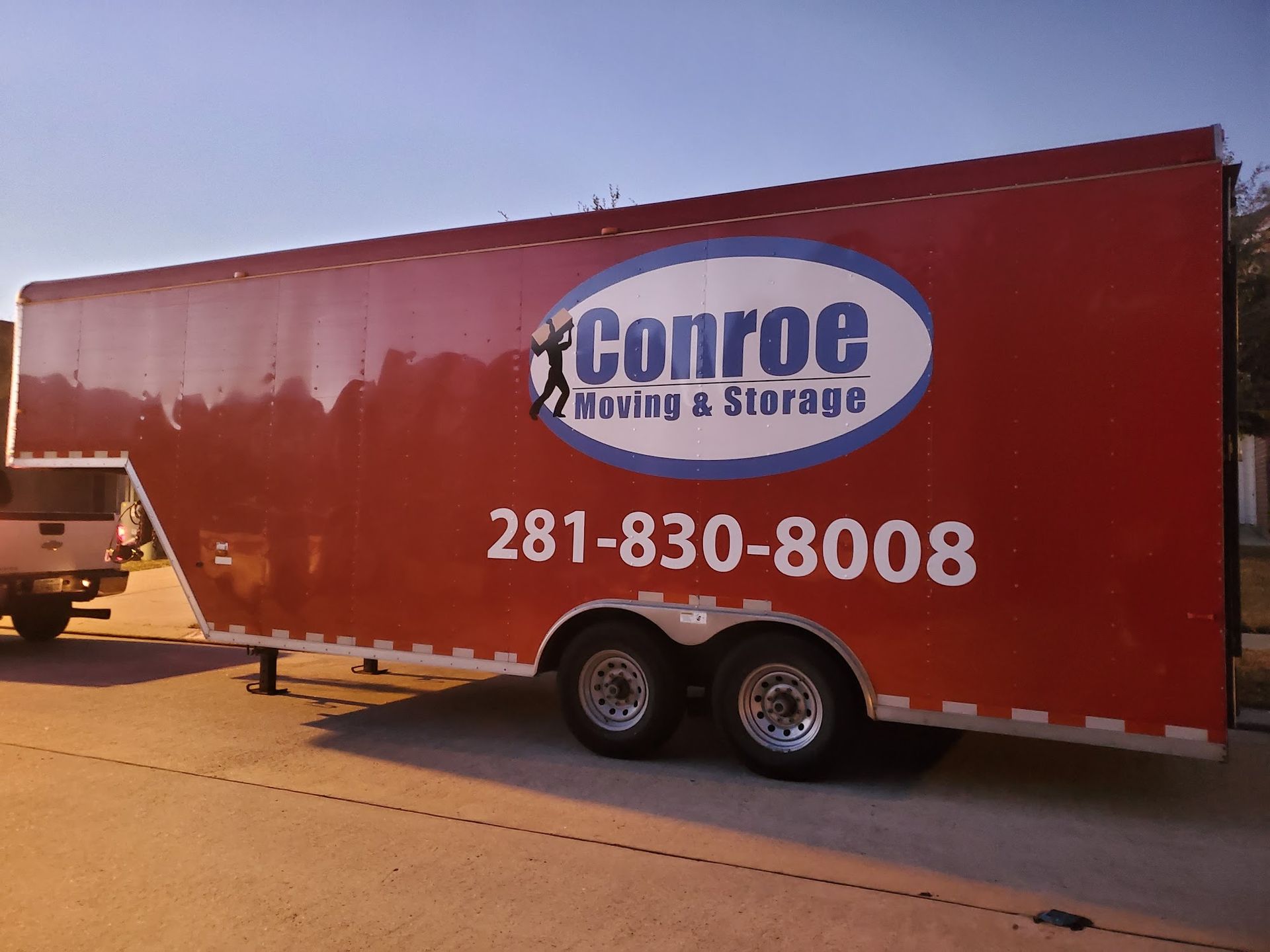 Red moving truck trailer with Conroe Moving & Storage logo and phone number 281-830-8008