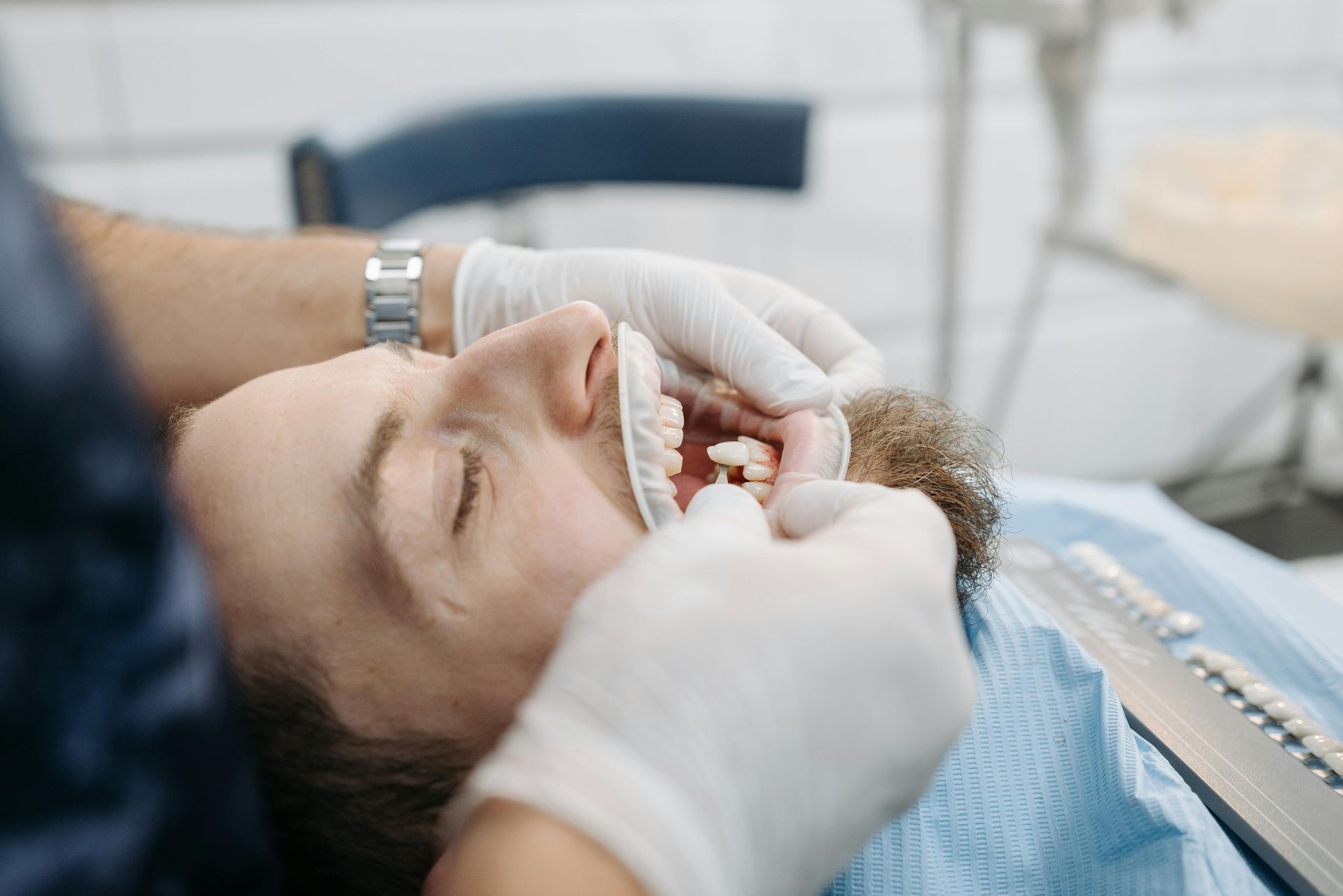 Dentist adjusting a patient's mouth with gloved hands during a dental procedure