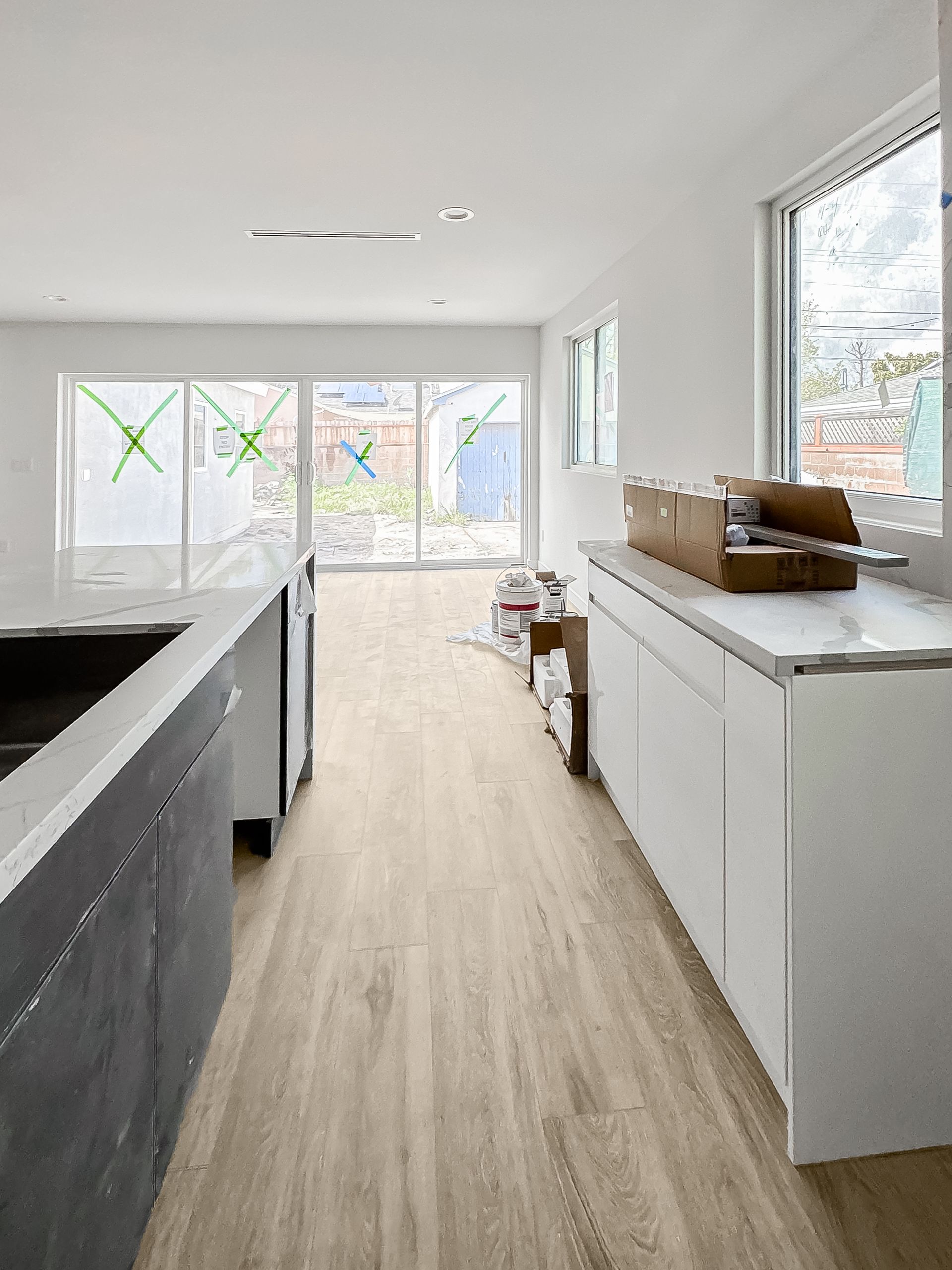 Bright modern kitchen with white cabinets, wood floors, and large windows letting in natural light
