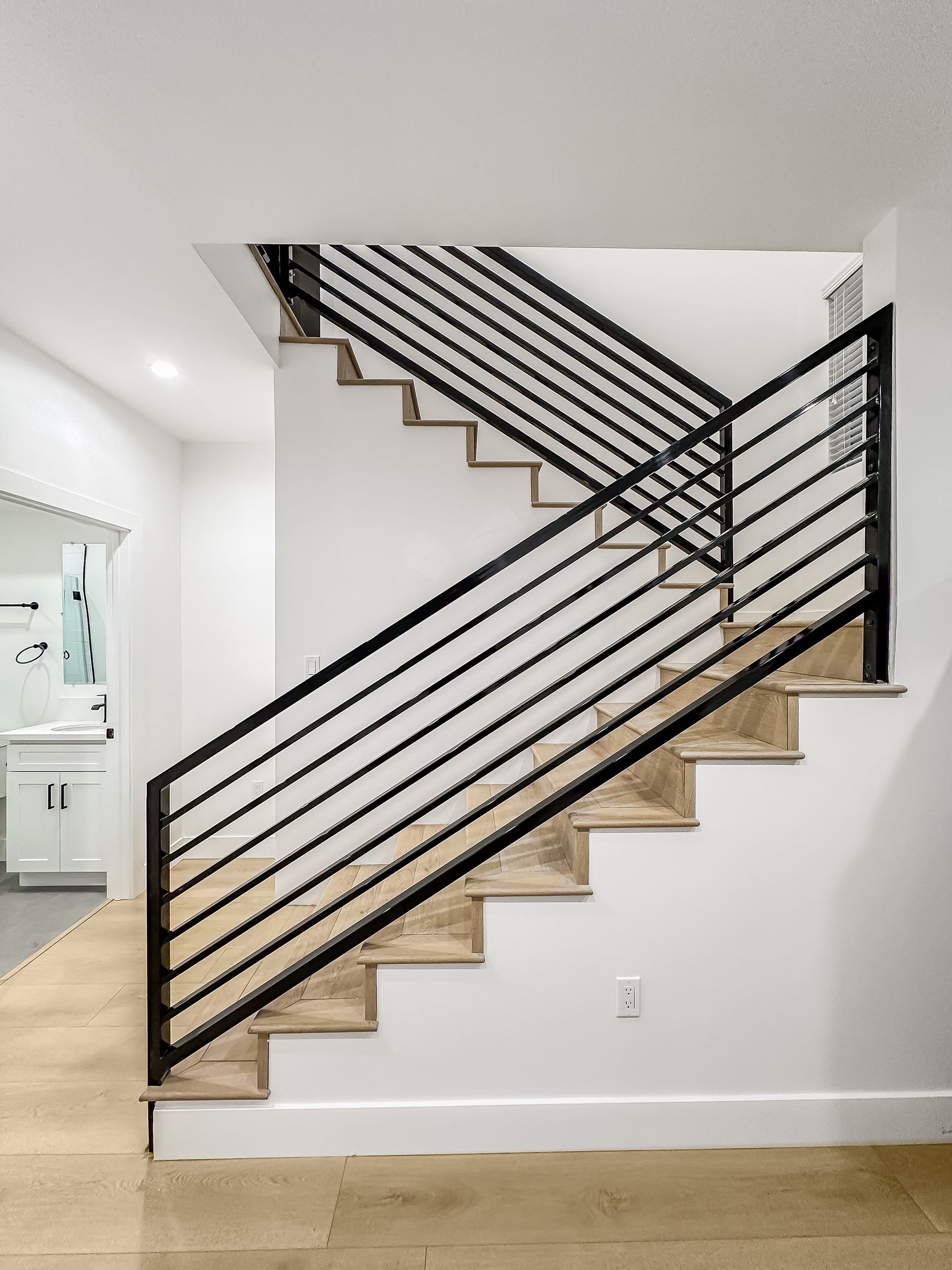 Modern staircase with black metal railings in a bright white hallway