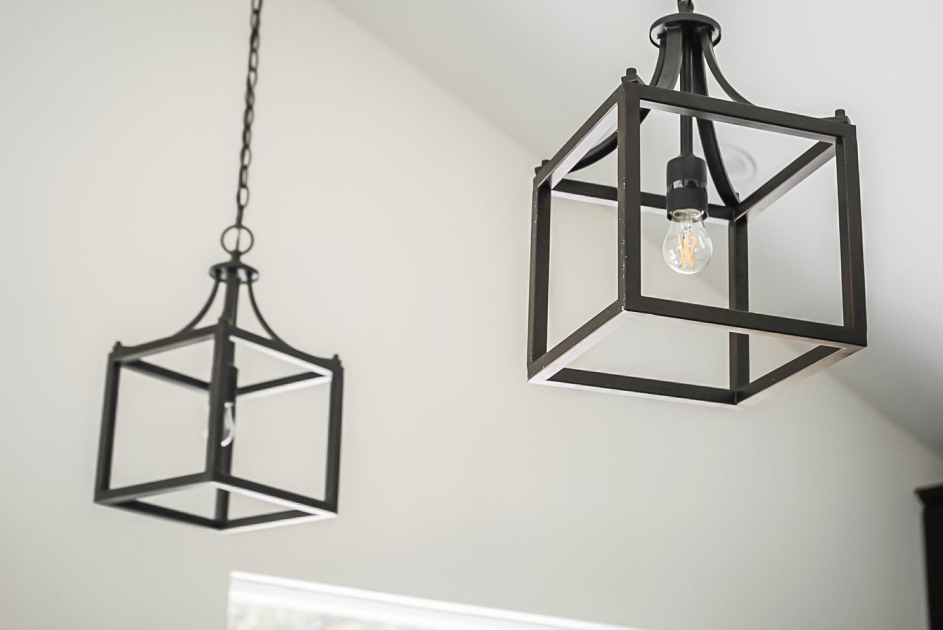 Two black geometric pendant lights hanging from a white ceiling