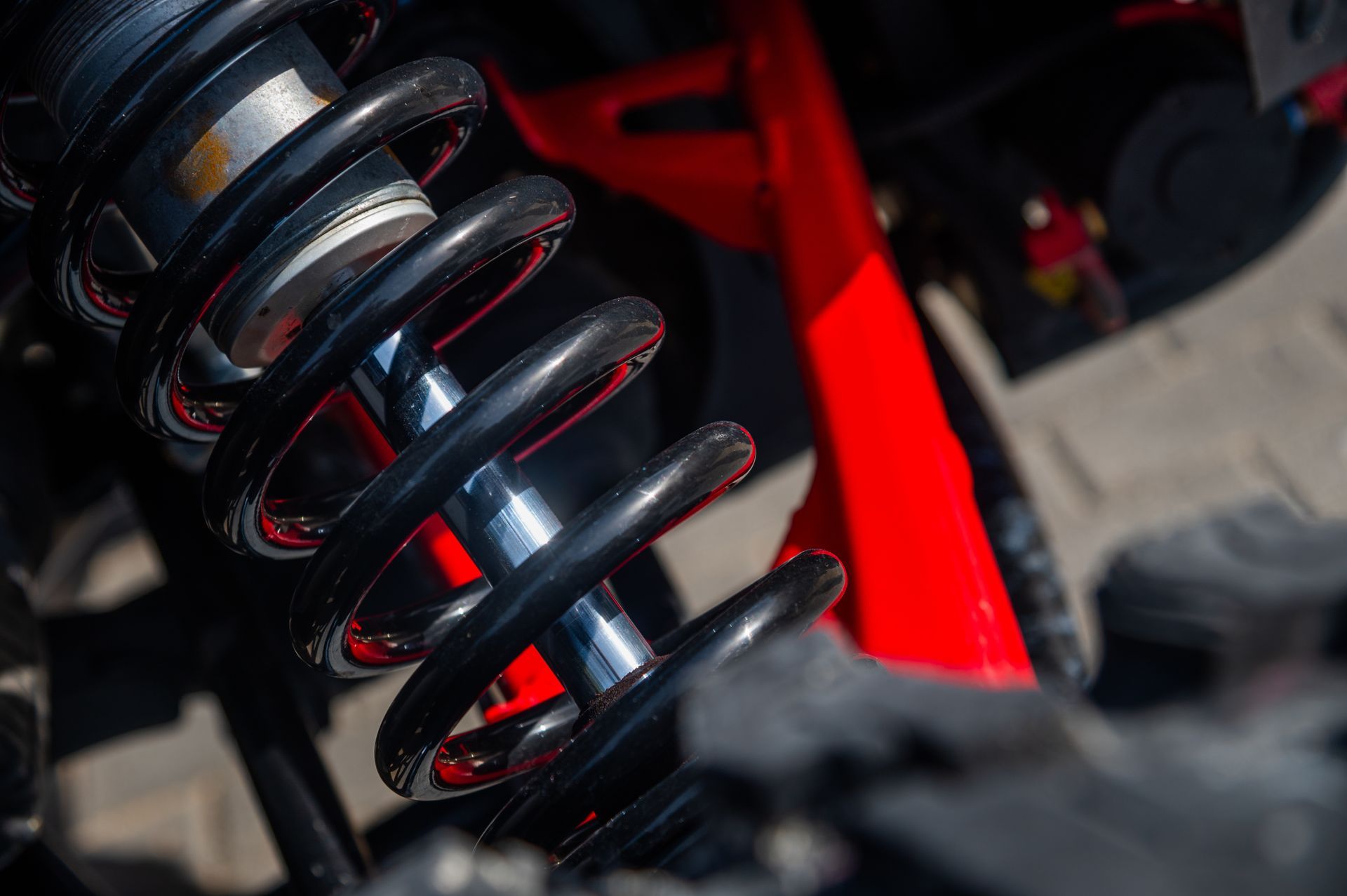 Close-up of a red and black suspension spring on a vehicle chassis