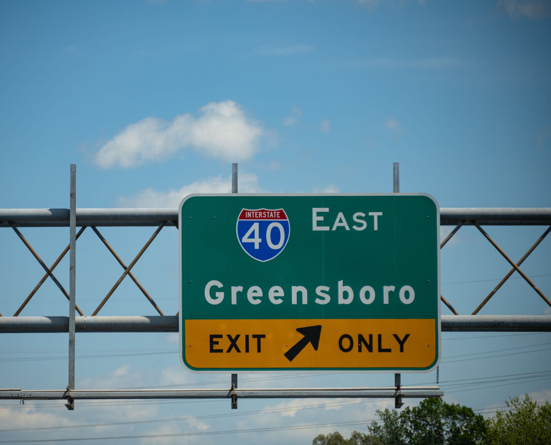 I-40 East sign for Greensboro, yellow Exit Only panel against blue sky