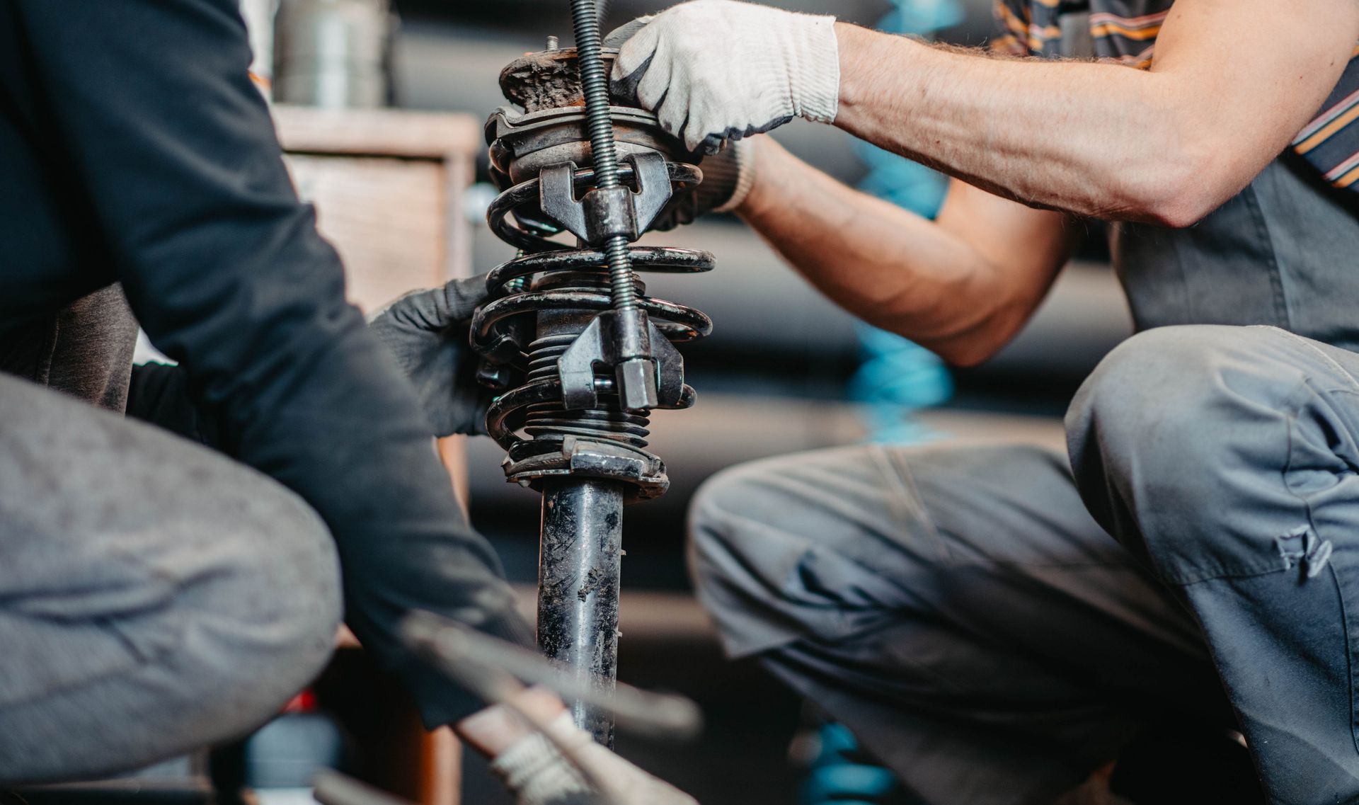Mechanic team using tools to repair a car suspension component in a garage