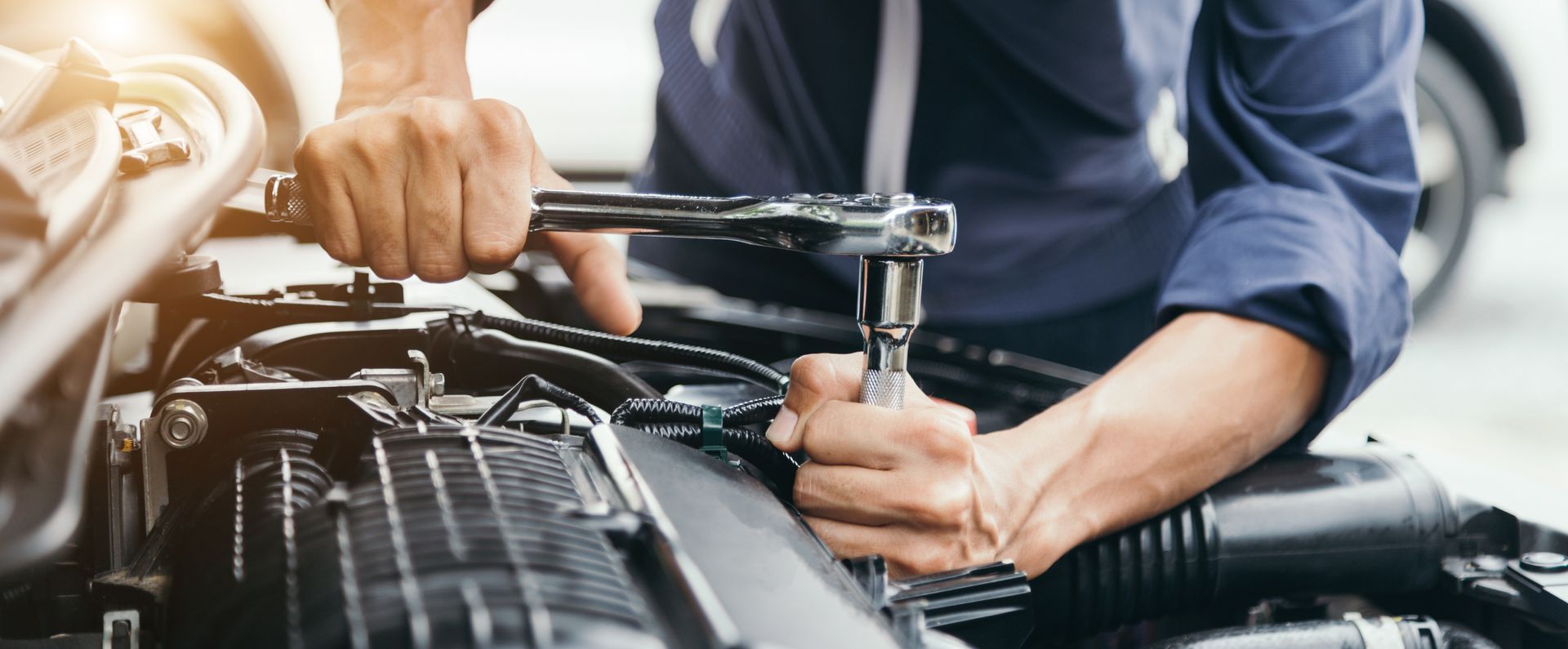 Mechanic using a wrench to repair a car engine in a garage