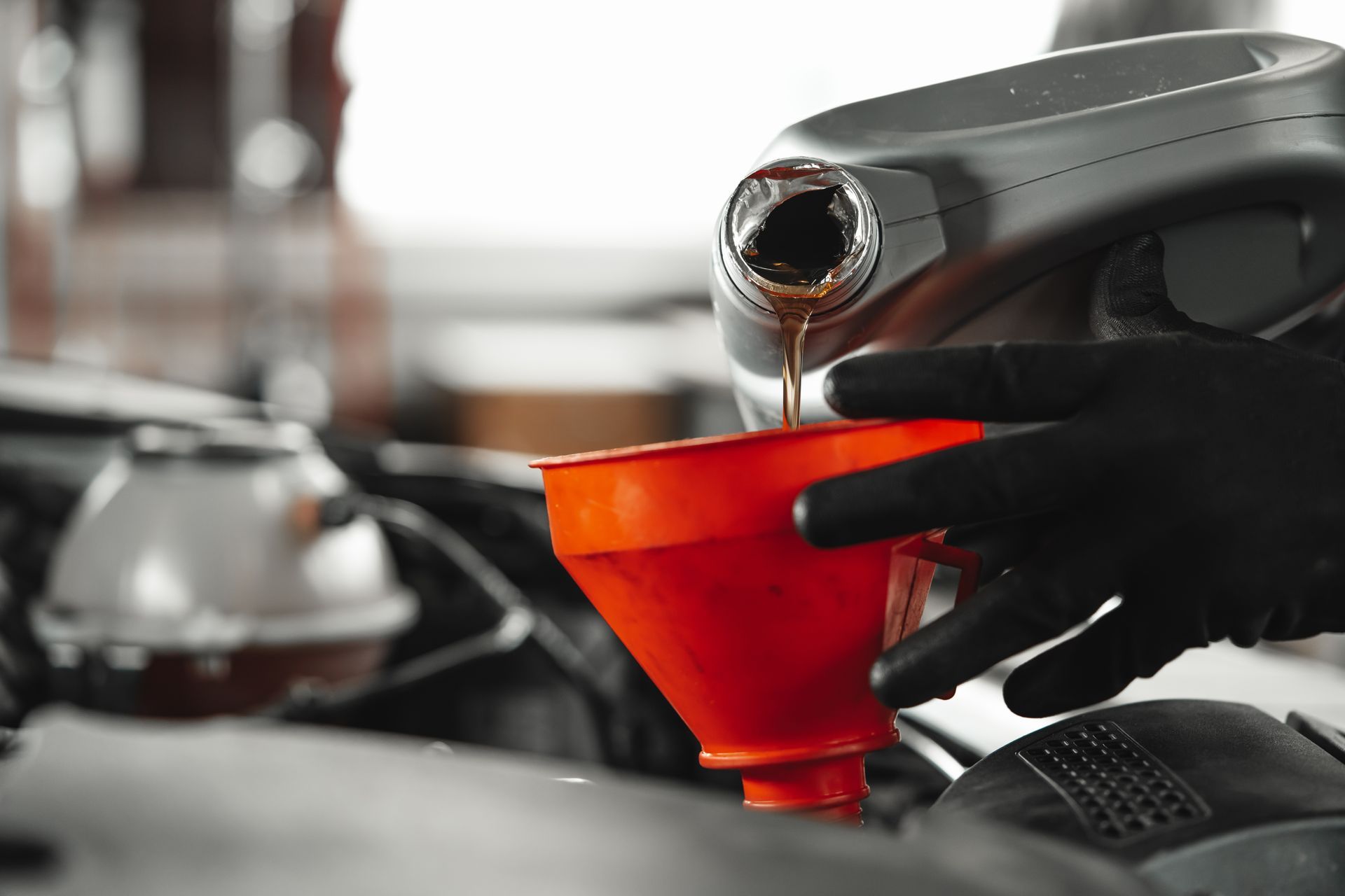 Coffee being poured from a silver kettle into a red funnel over a drip brewer.